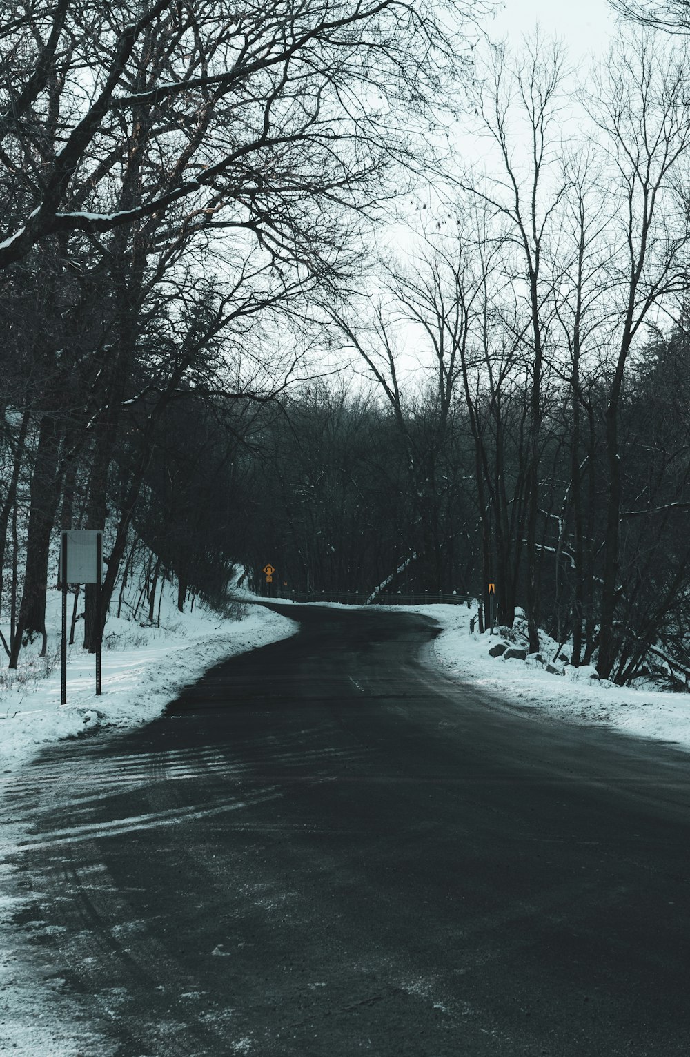 person in black jacket walking on snow covered road during daytime