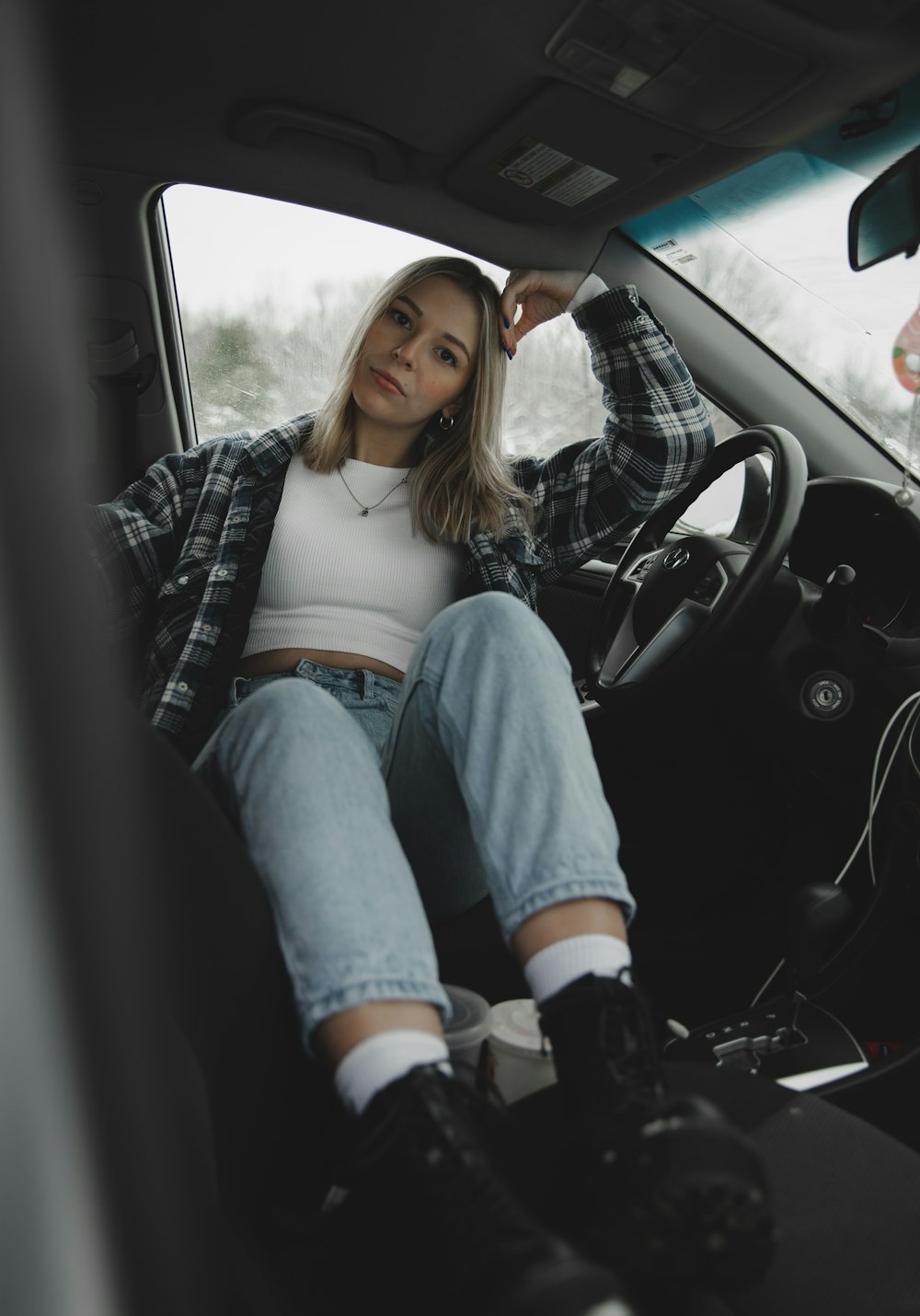 woman in blue denim jeans and white tank top sitting on car seat