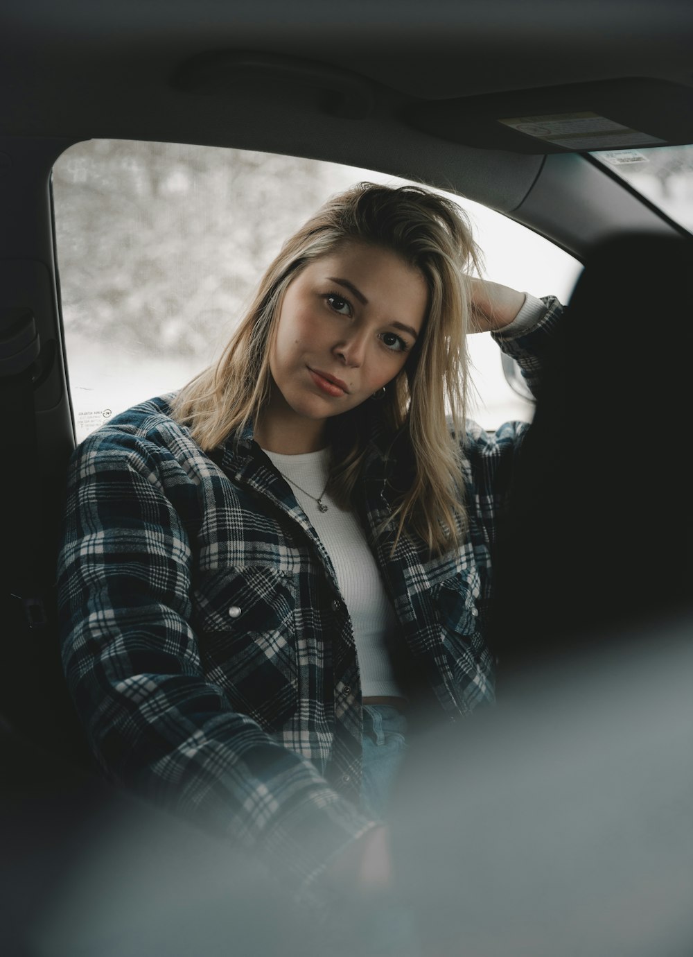 woman in black and white plaid dress shirt sitting inside car during daytime