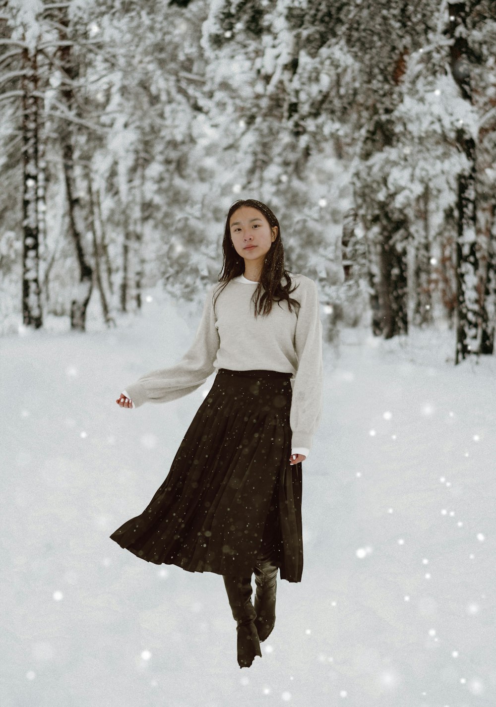 woman in white long sleeve shirt and black skirt standing on snow covered ground
