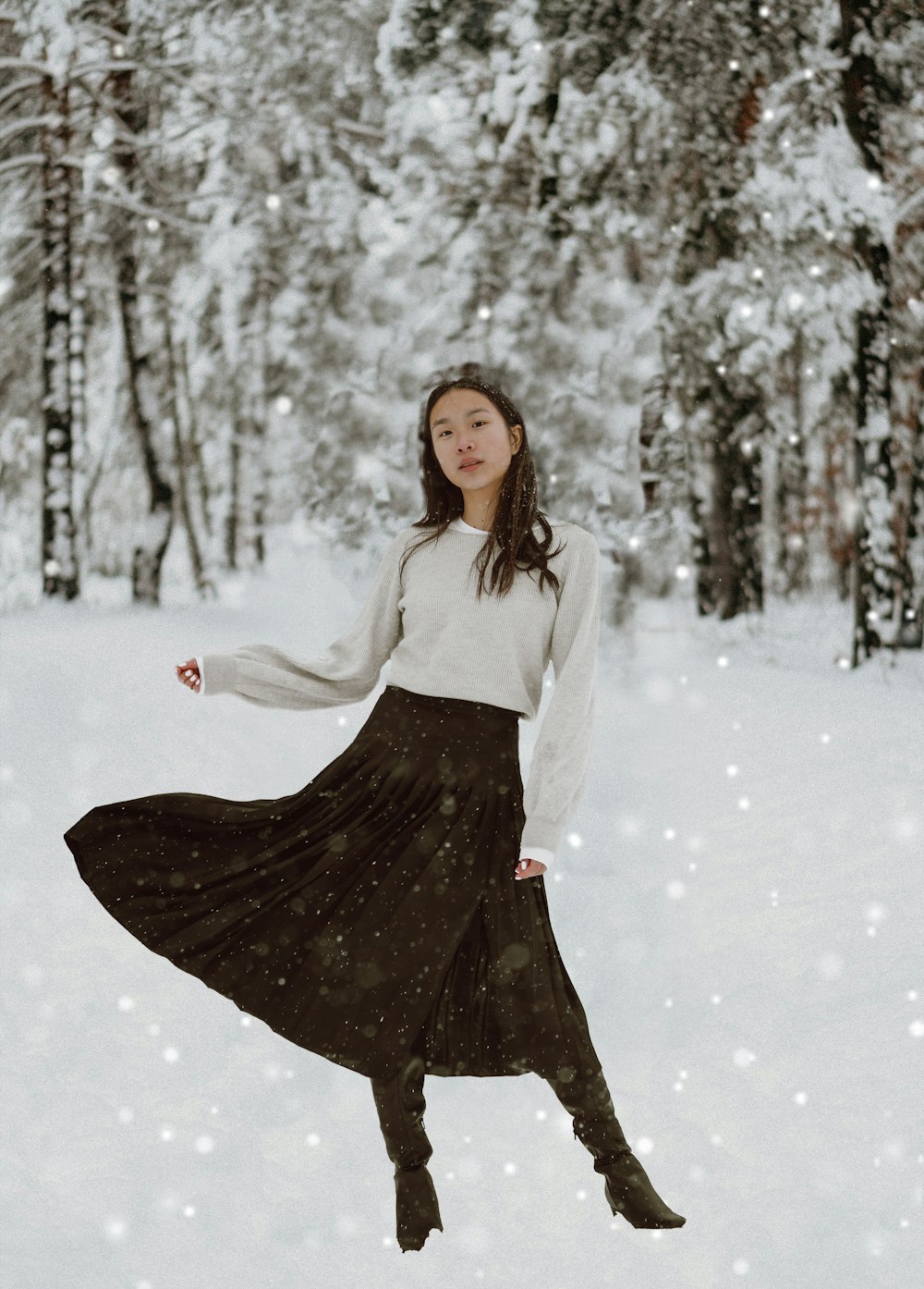 woman in white long sleeve shirt and black skirt standing on snow covered ground during daytime
