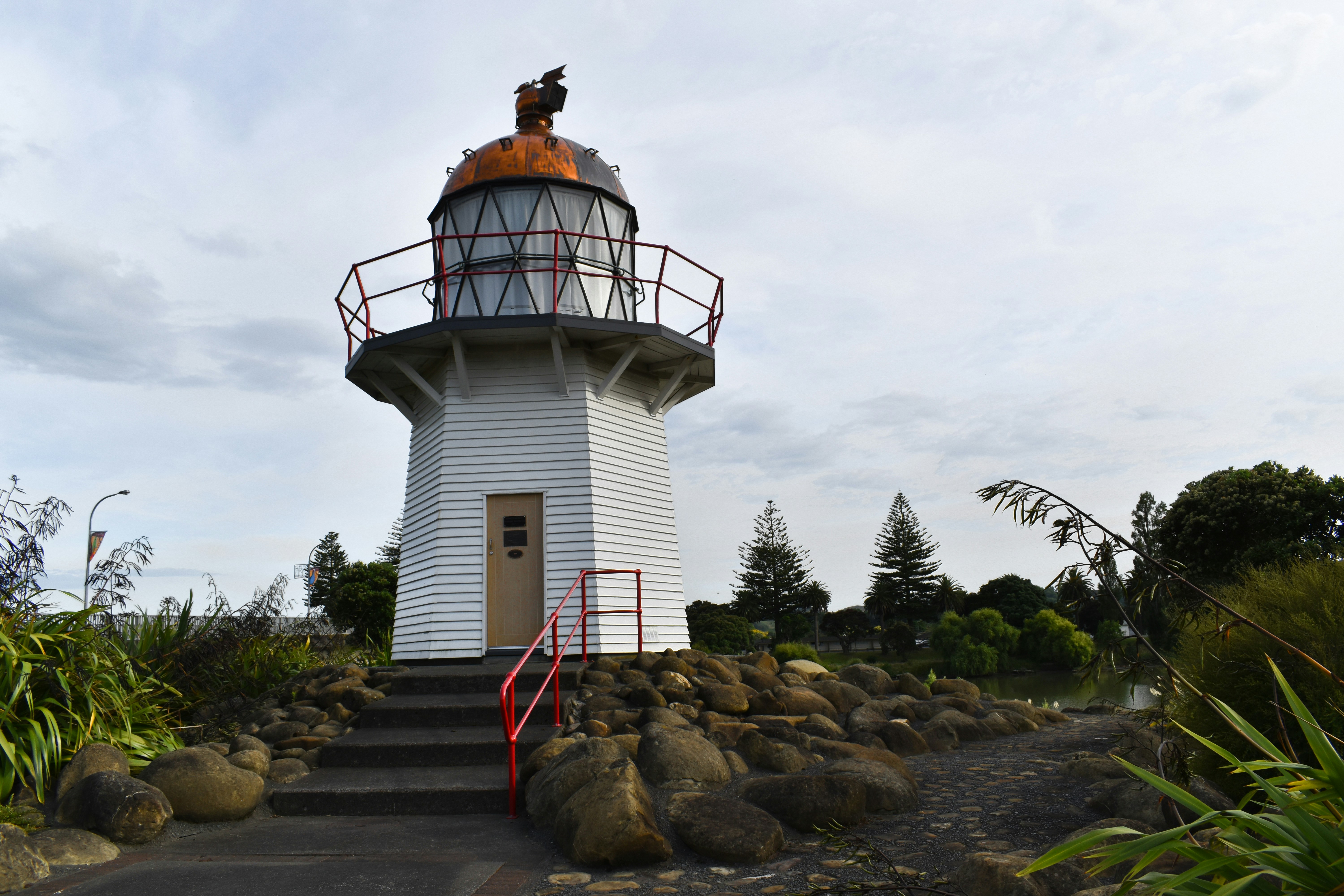 Phare blanc et rouge sous un ciel nuageux pendant la journée