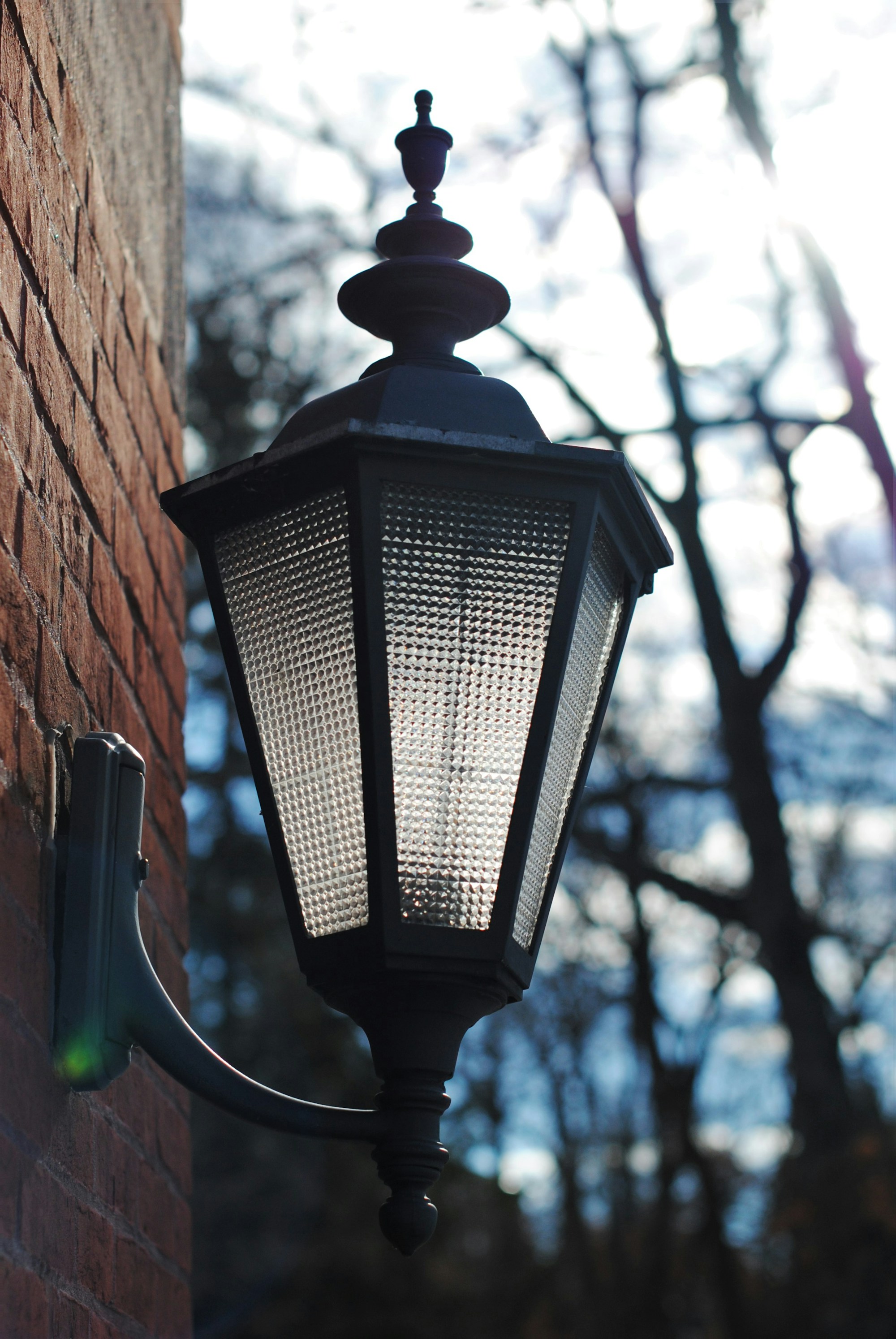 Black exterior wall sconce mounted on a brown concrete wall beside a doorway