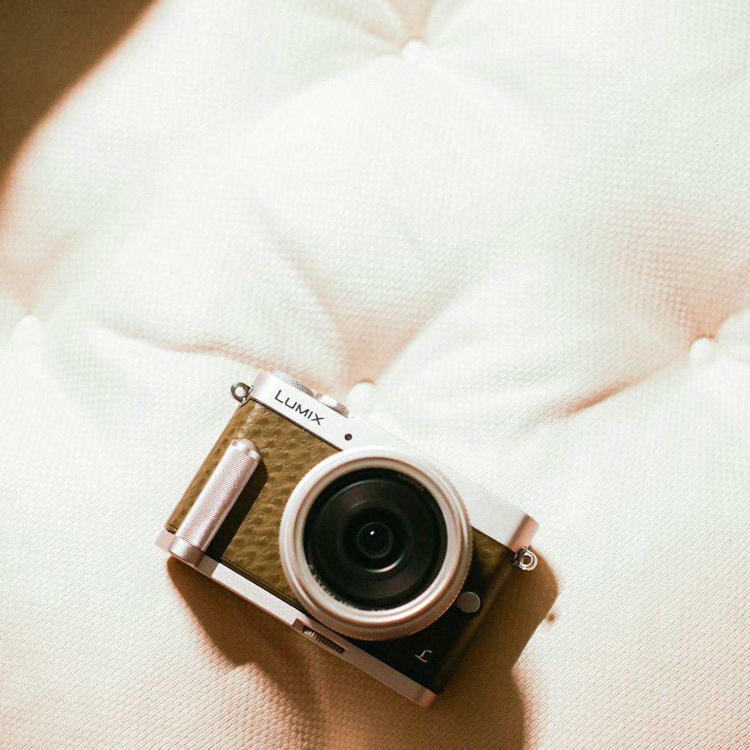 silver and black point and shoot camera on white textile