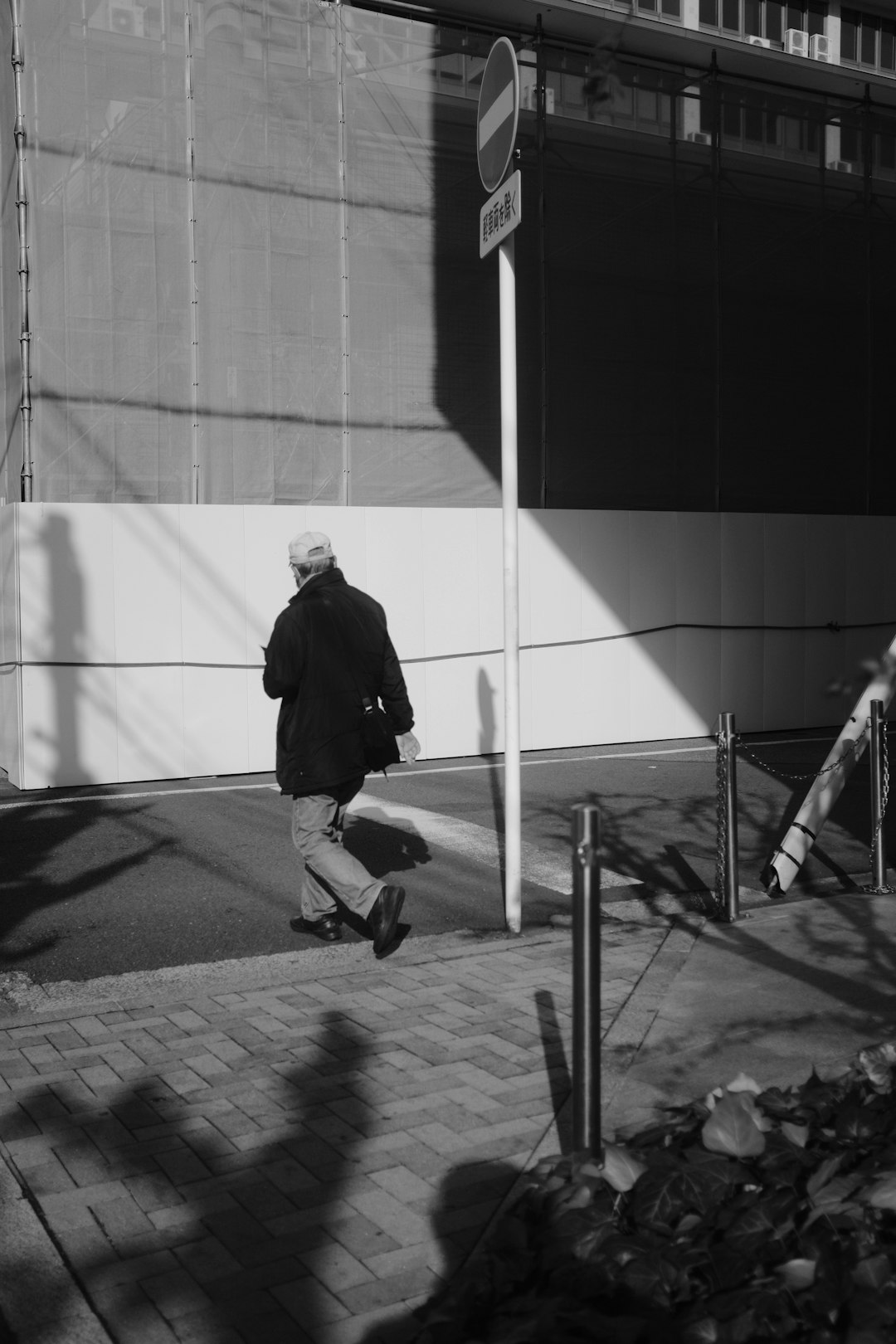man in black jacket walking on sidewalk