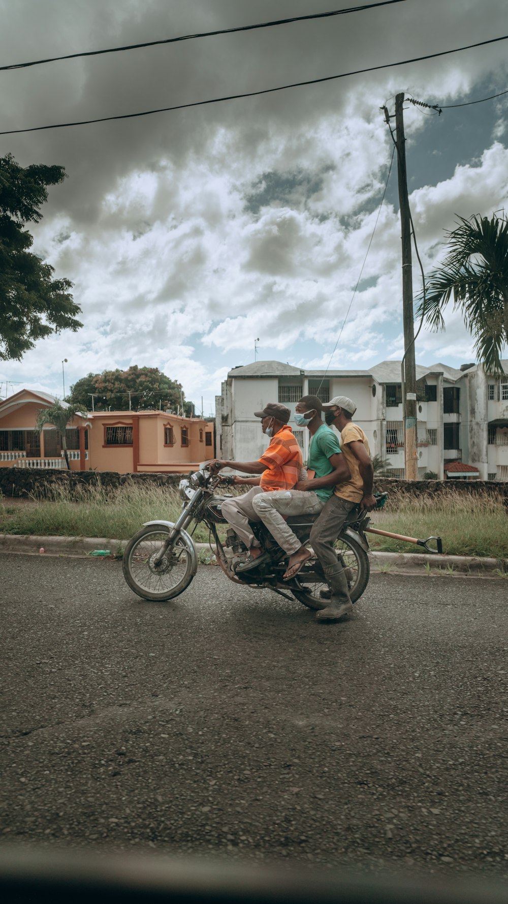 man in green t-shirt riding on black motorcycle during daytime