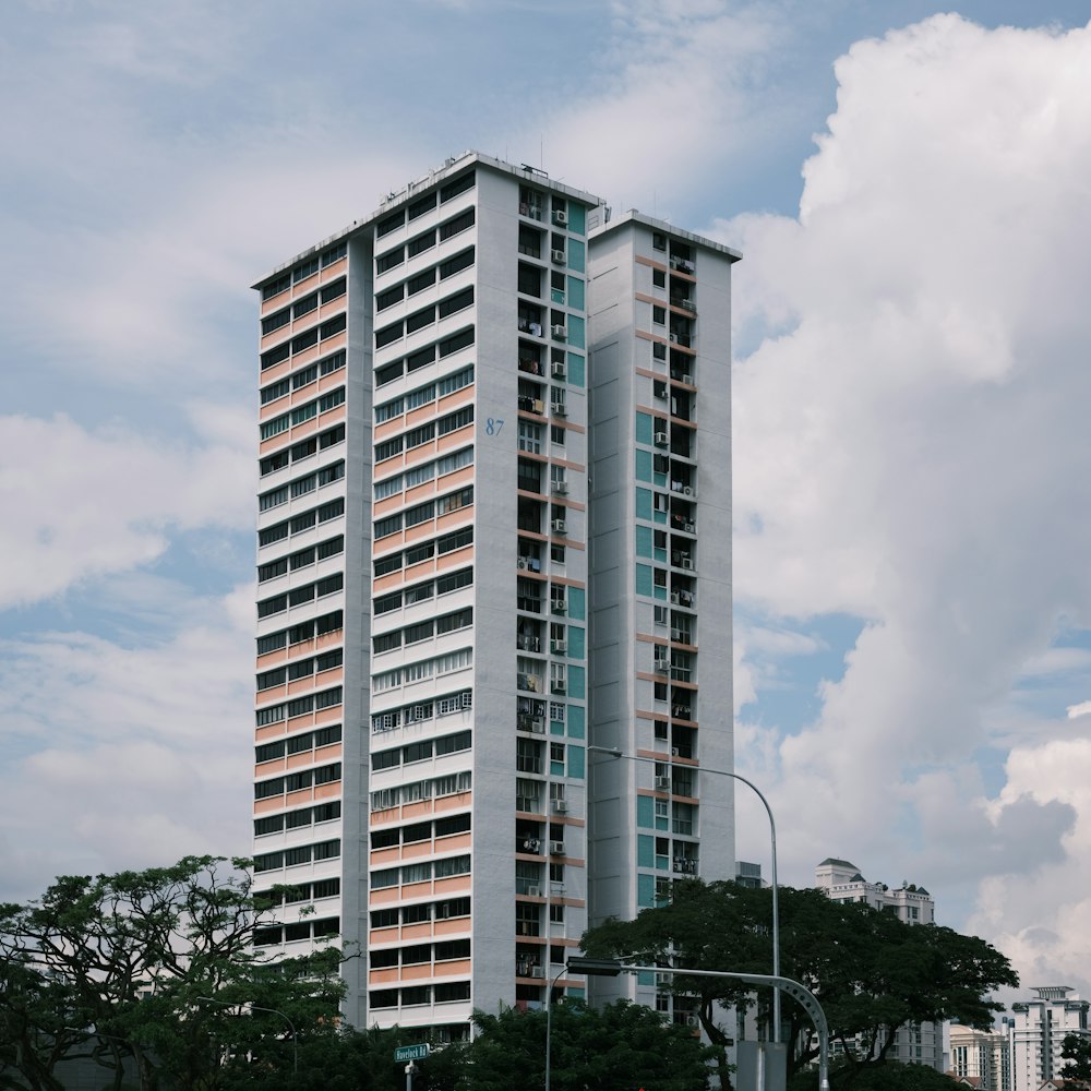 edifício de concreto branco perto de árvores verdes sob nuvens brancas durante o dia