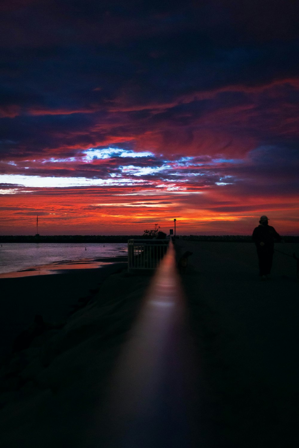 silhouette of 2 person standing on wooden dock during sunset