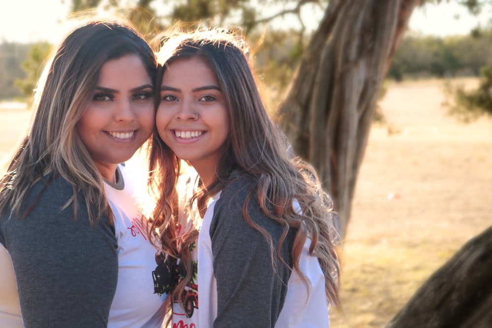 2 women smiling near trees during daytime