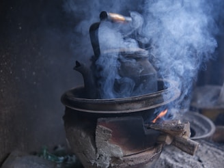 A traditional kiln with smoke rising, where coconut shells slowly turn into charcoal.
