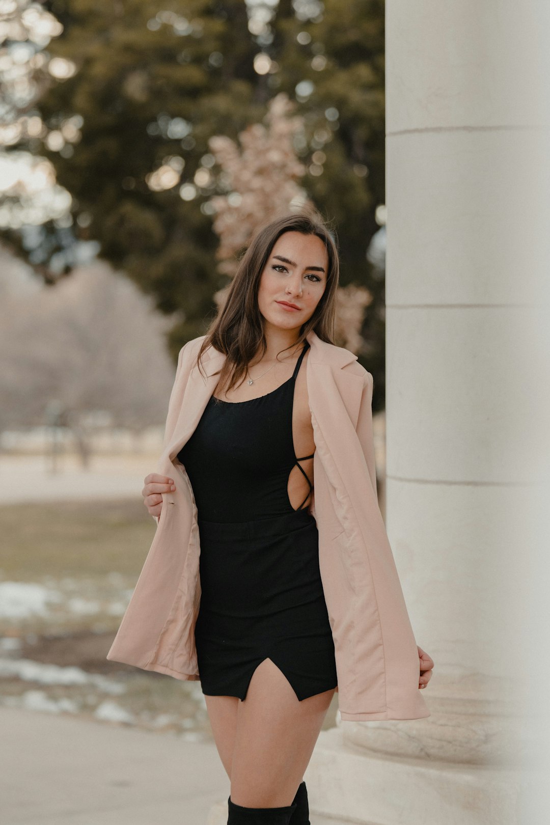 woman in black tank top and pink blazer standing near white concrete wall during daytime