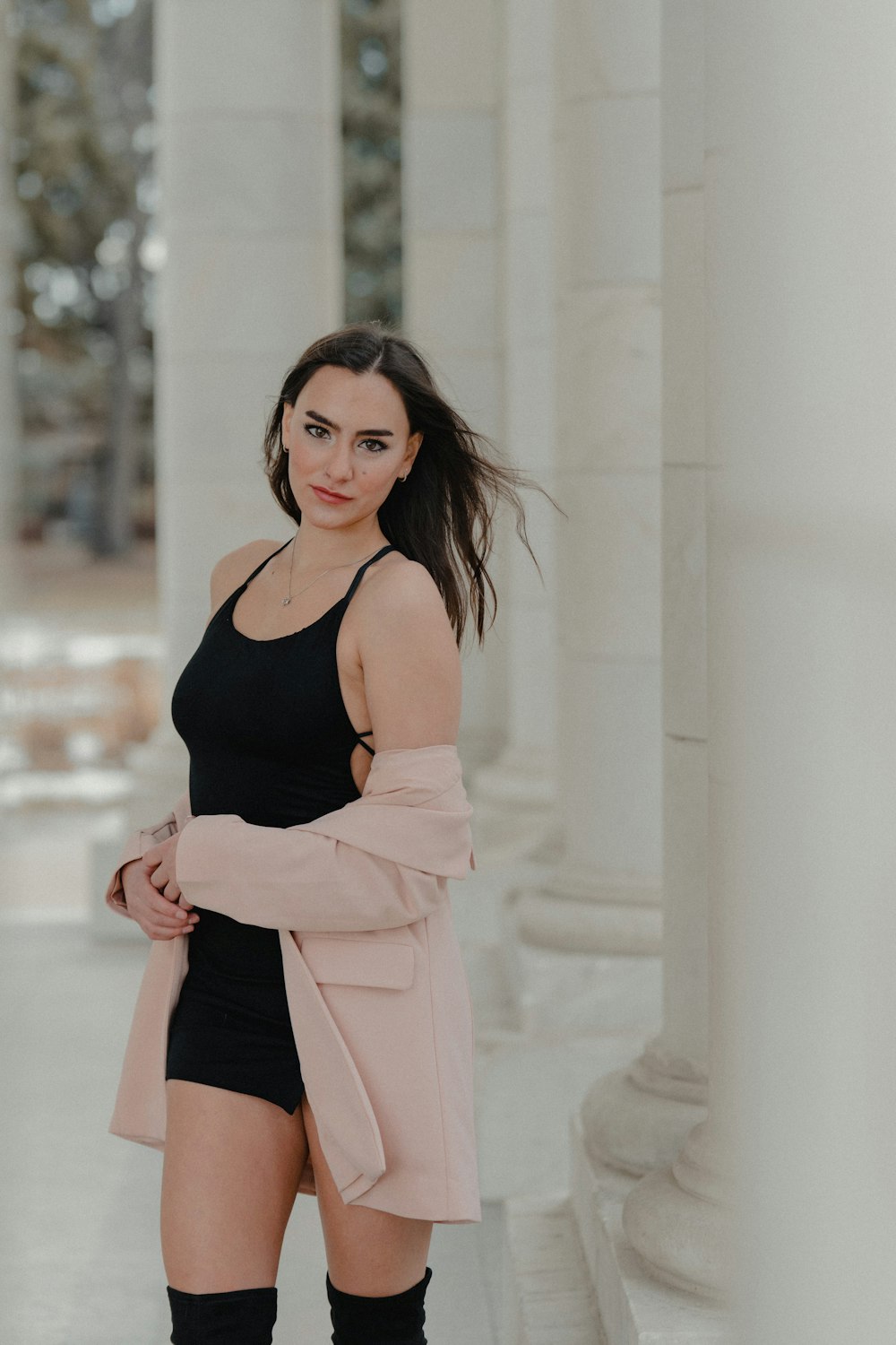 woman in black tank top and pink pants standing near white wall