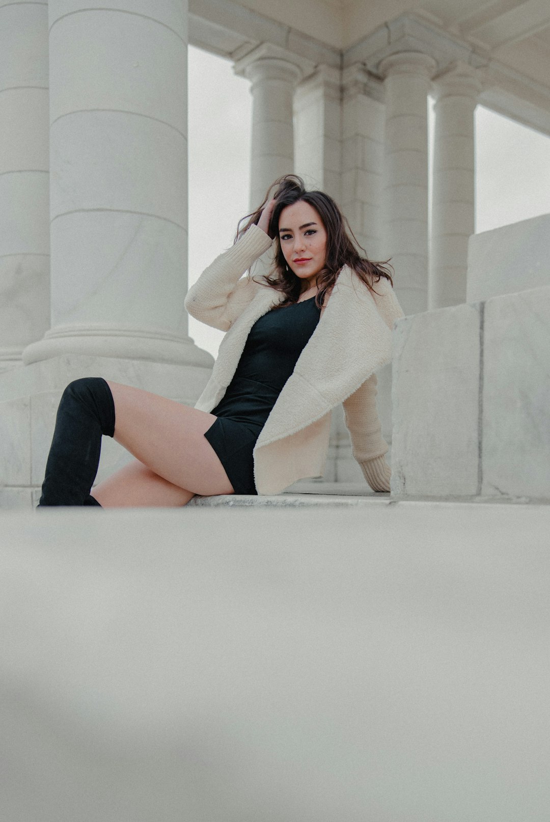 woman in white sweater sitting on white concrete bench