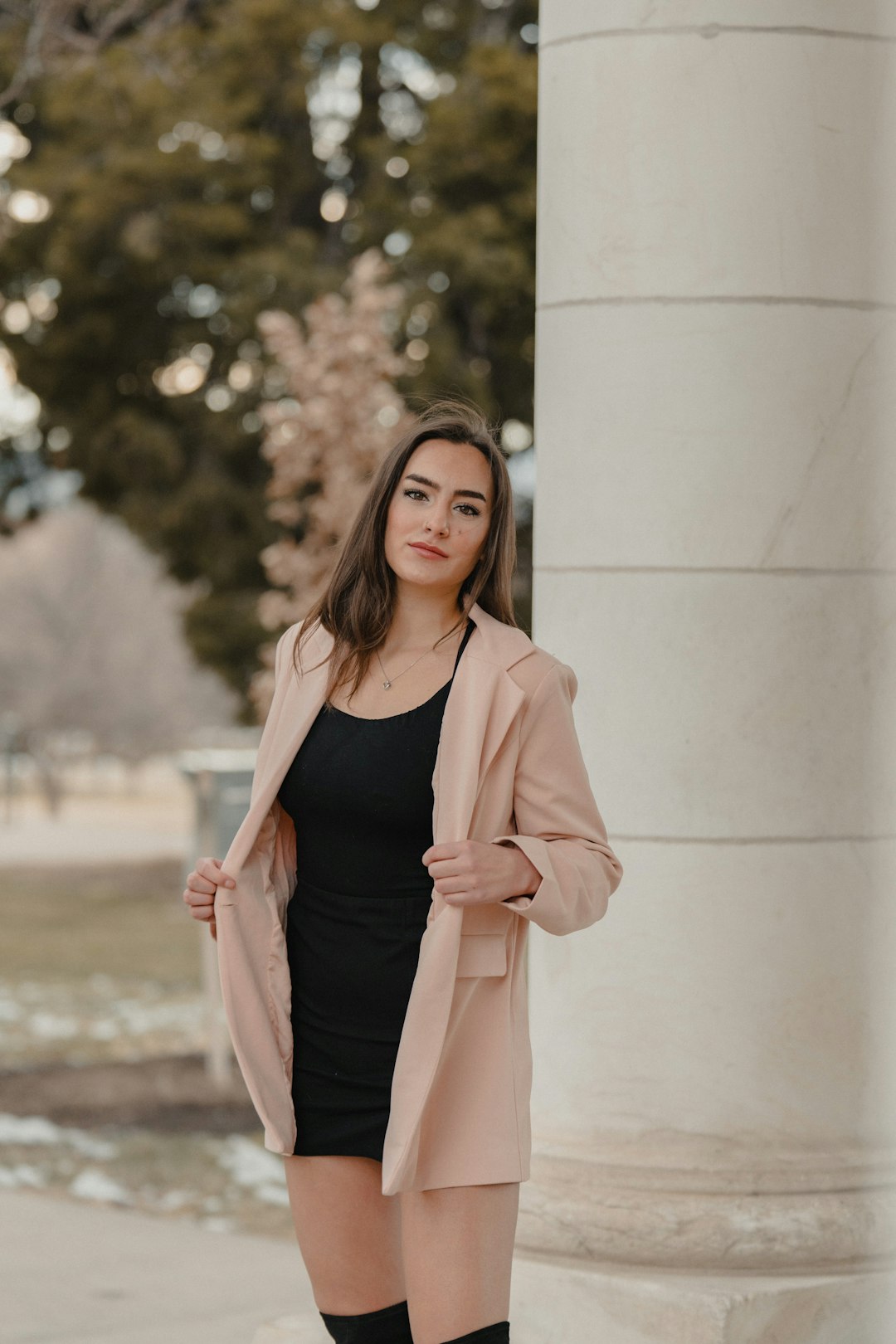 woman in pink blazer standing near white wall during daytime