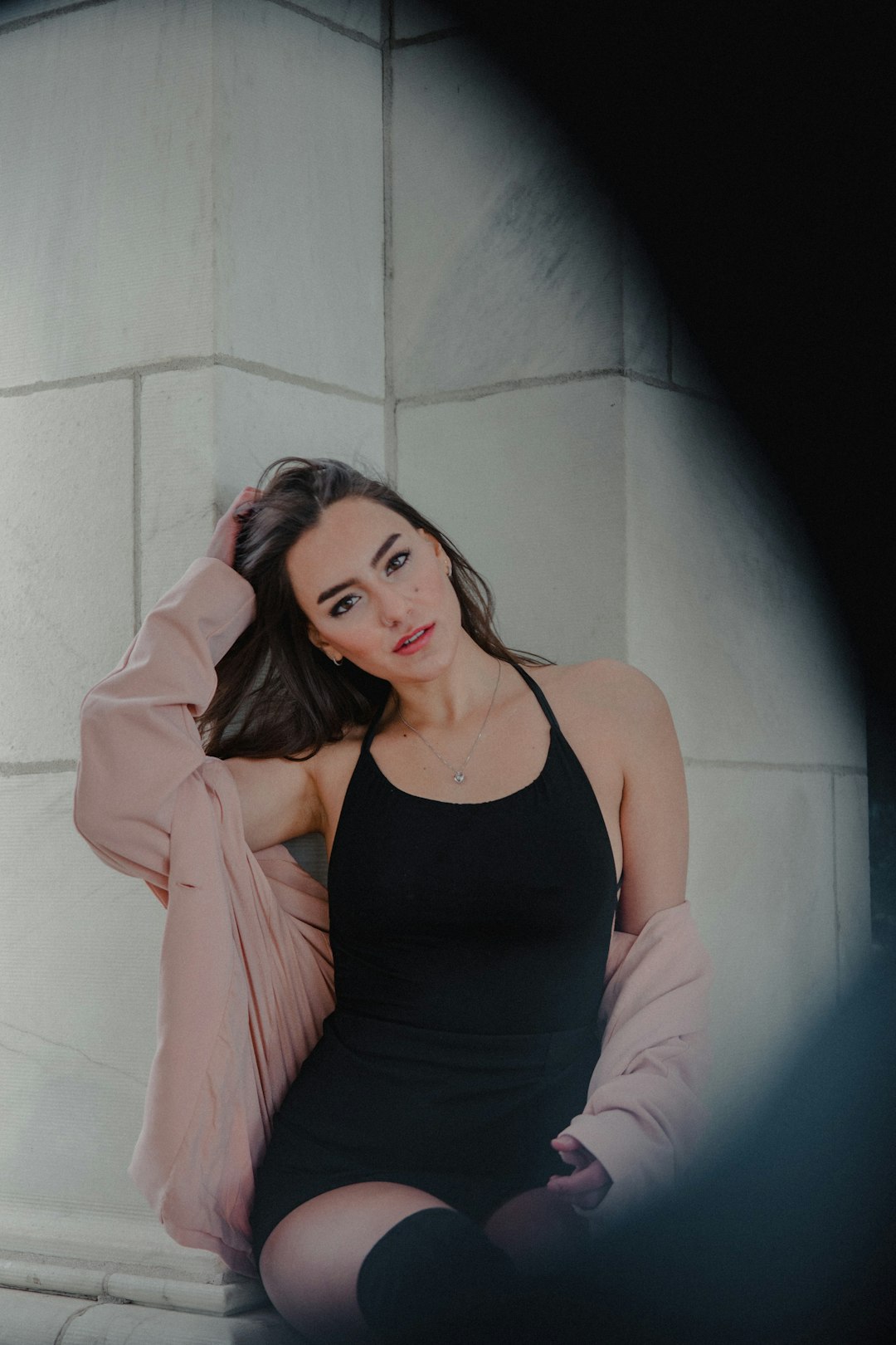 woman in black tank top leaning on white wall