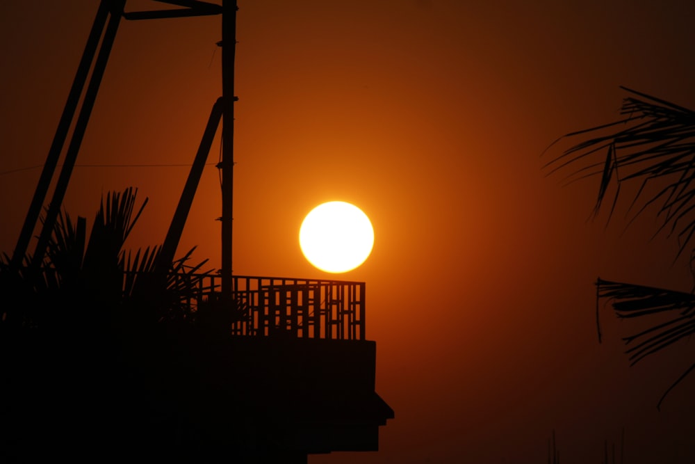 Die Sonne geht über einem Gebäude und Palmen unter