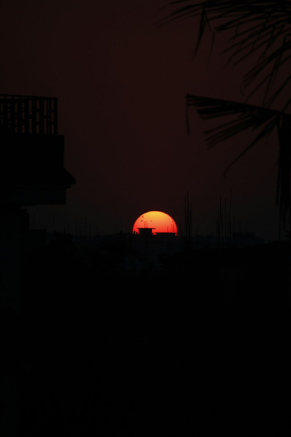 the sun is setting behind a building in the dark