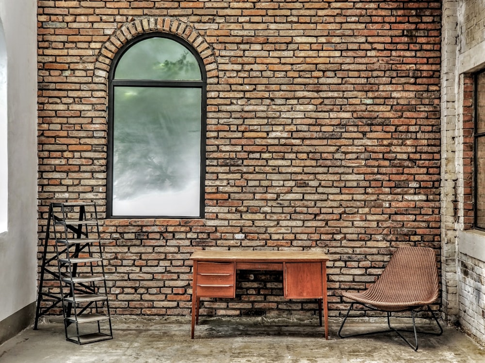 chaise en bois marron à côté d’un mur de briques brunes