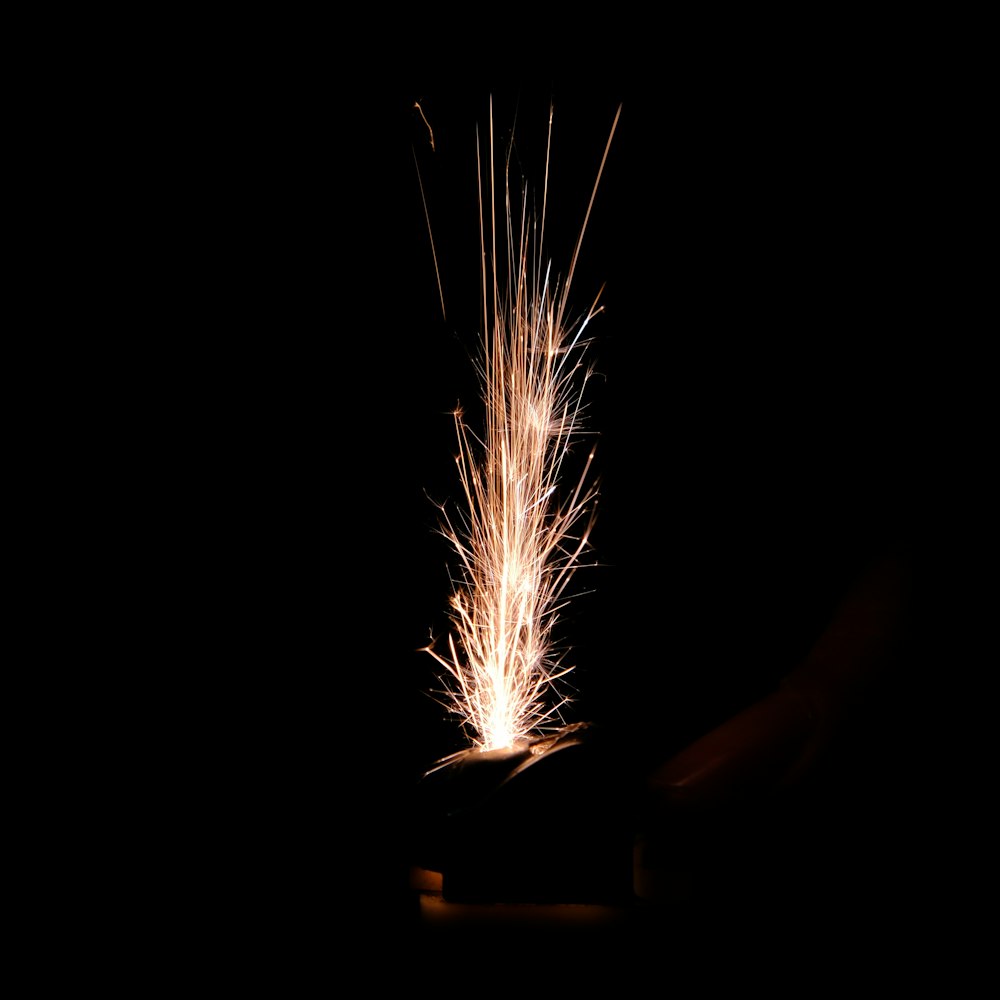 a person holding a lit sparkler in their hand