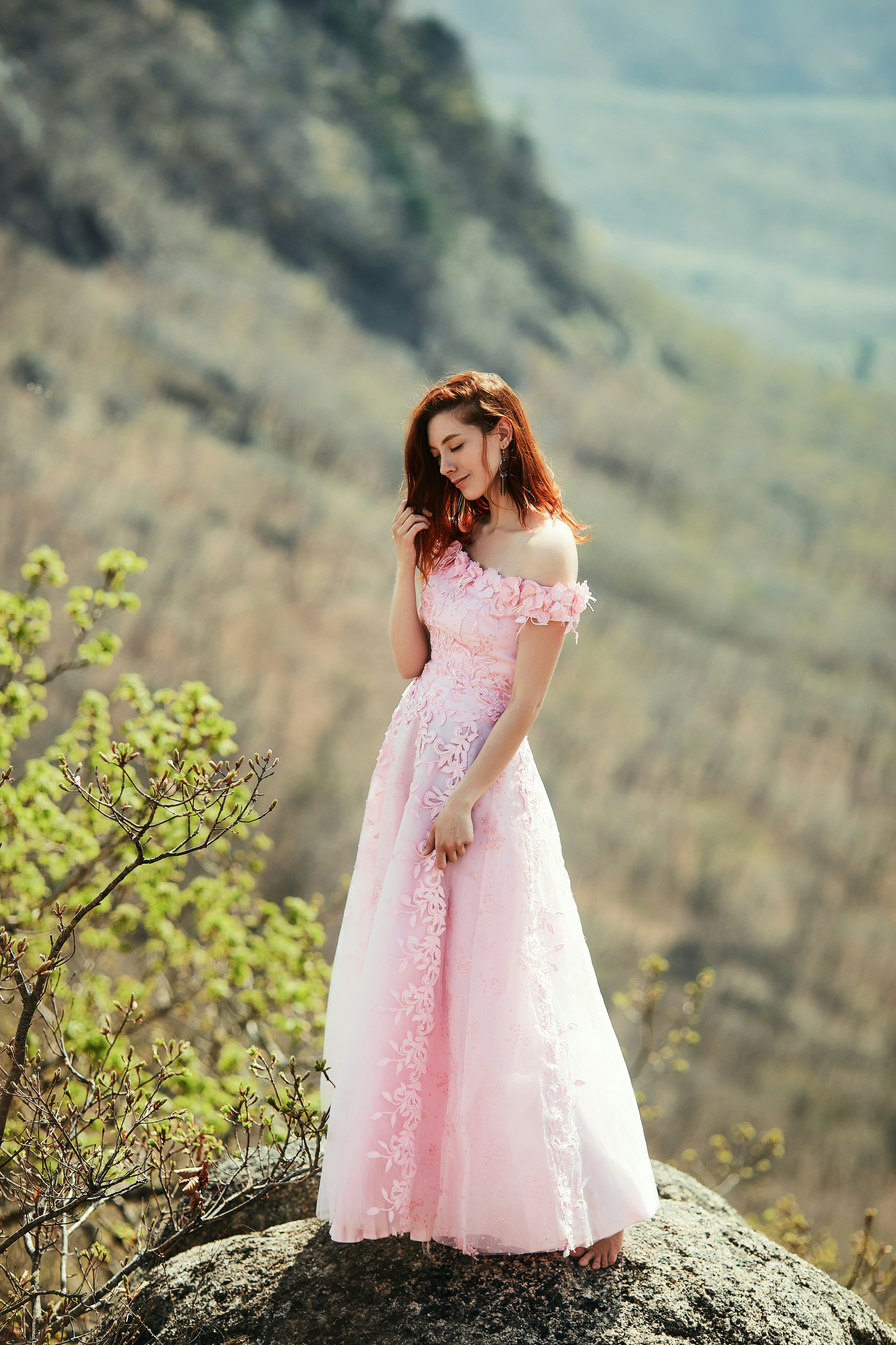 woman in pink dress standing near green tree during daytime