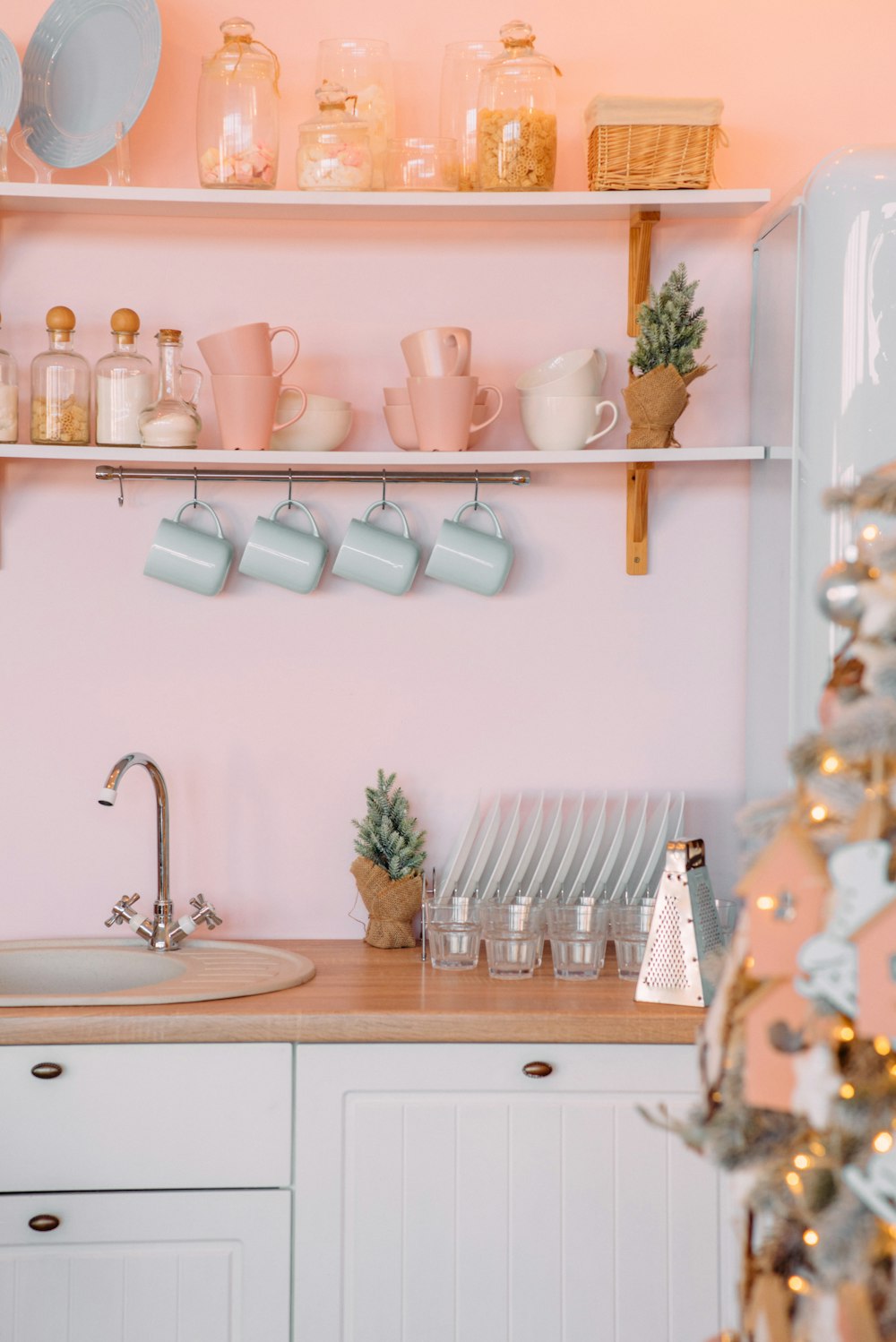 una cucina con pareti rosa e armadi bianchi