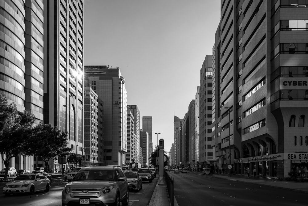 grayscale photo of cars on road near high rise buildings