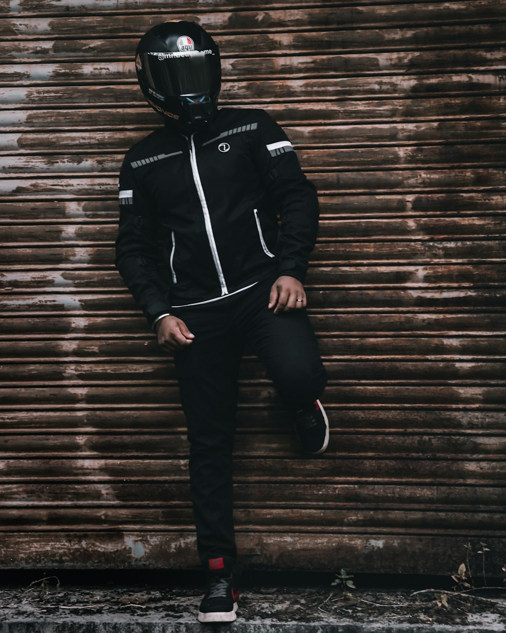 man in black jacket and black pants wearing black helmet walking on wooden stairs