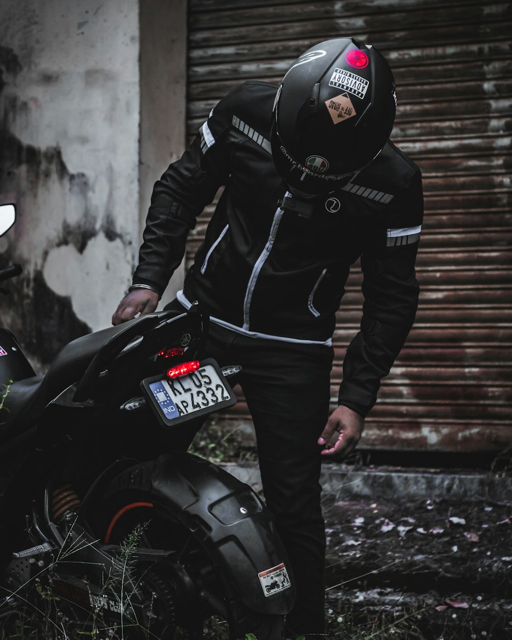 man in black leather jacket and black pants standing beside black motorcycle
