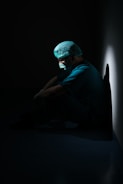 man in green shirt and blue knit cap sitting on floor