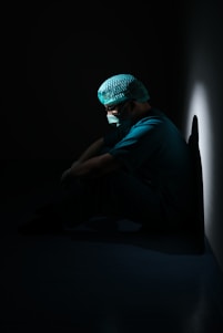 man in green shirt and blue knit cap sitting on floor