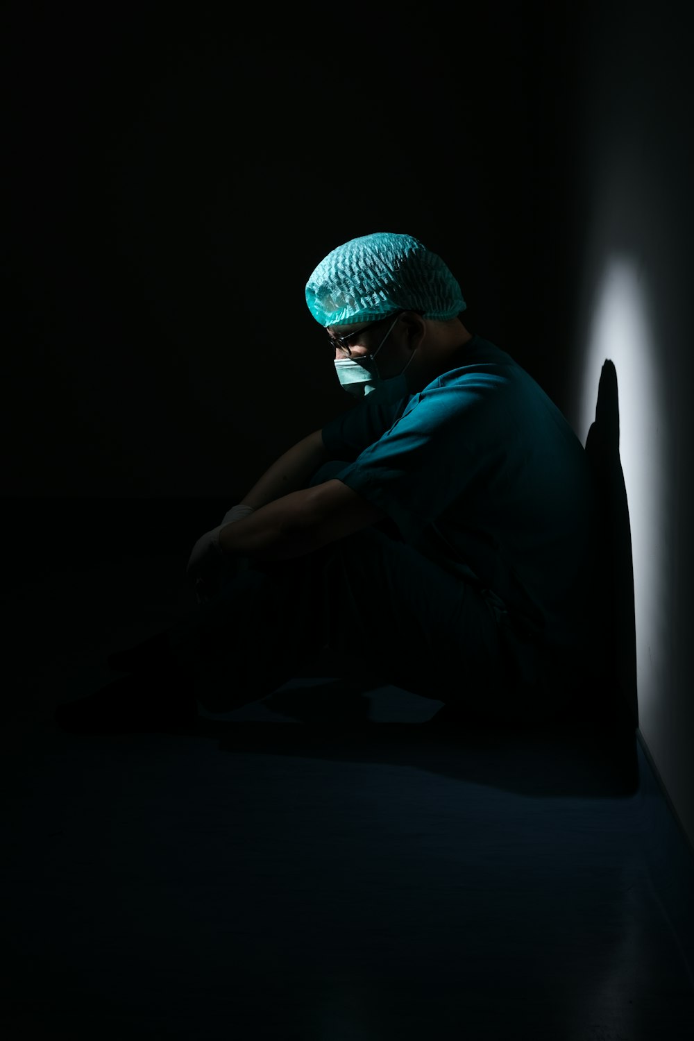 hombre con camisa verde y gorro de punto azul sentado en el suelo