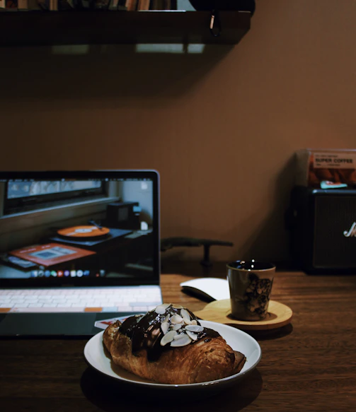 A cozy workspace with a record player, fashion sketches pinned on the wall, and a well-worn philosophy book open on the desk.