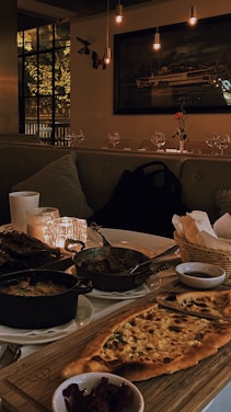 A warm, inviting dining area with colorful plates of paneer pizza and starters on the table.