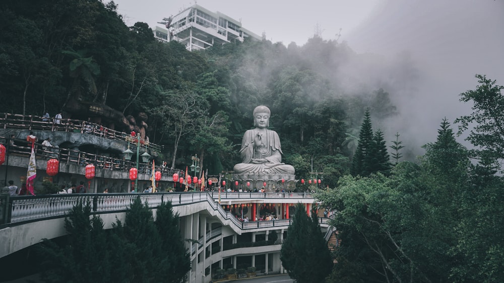 gray statue of man on top of white boat surrounded by green trees during daytime