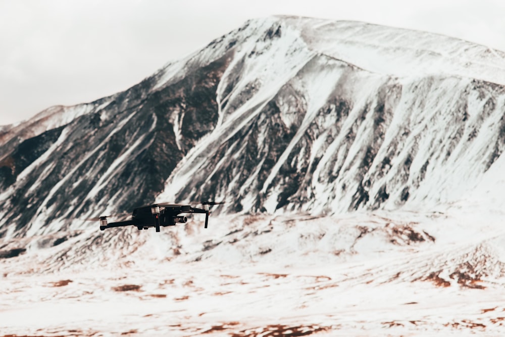 black helicopter flying over snow covered mountain