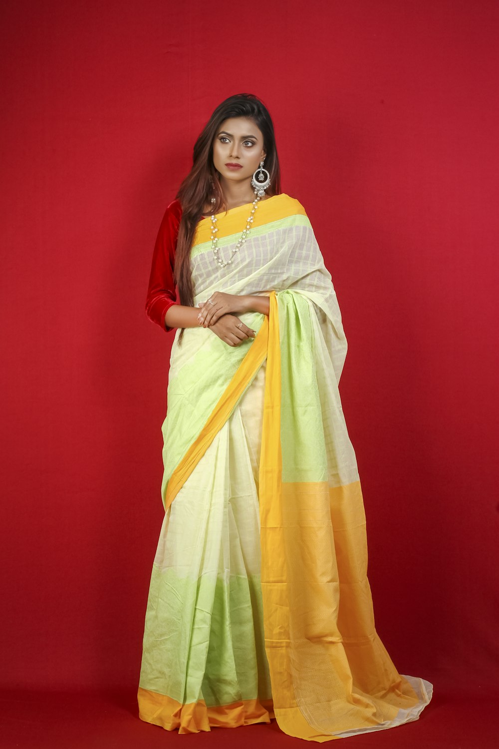woman in red and yellow sari standing beside red wall