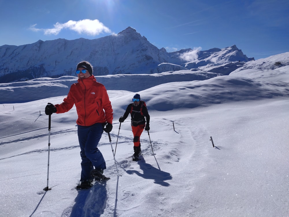 man in red jacket and black pants with black ski blades on snow covered mountain during