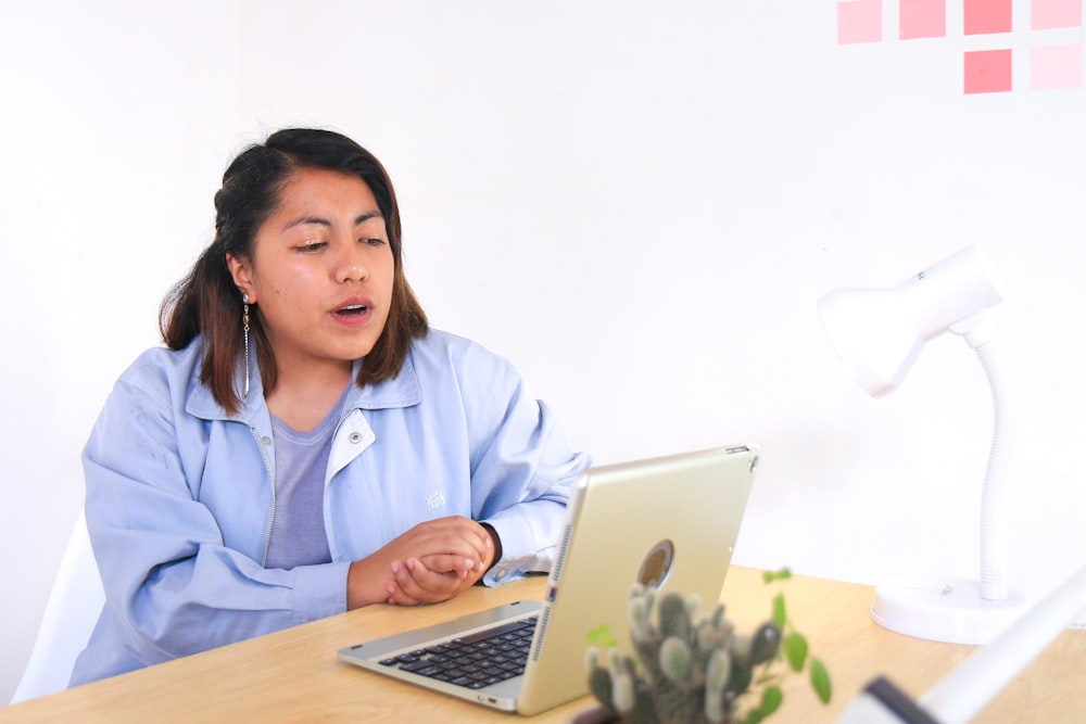 woman in blue dress shirt using macbook air