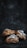 A cluster of three braided pastries lightly dusted with powdered sugar is placed against a dark, textured background. The pastries have a golden-brown color, with a flaky and twisted appearance that suggests a rich, buttery texture.