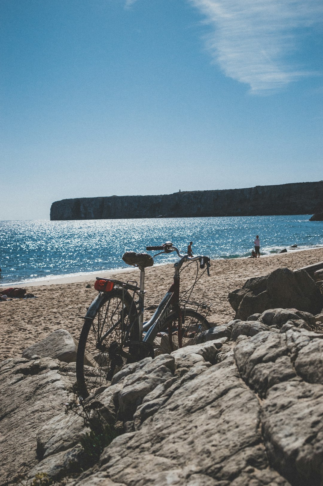 black bicycle on brown rock near body of water during daytime