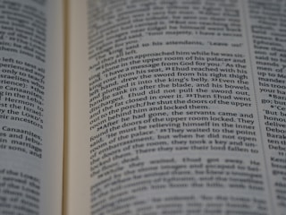 An open book with printed text. The focus is on two pages filled with paragraphs, with the text aligned in columns. The font is small and the page edges are slightly visible, suggesting it might be a religious or historical text.
