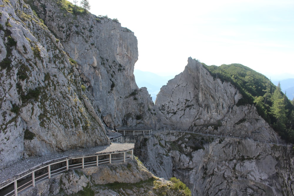 white wooden bridge on rocky mountain during daytime