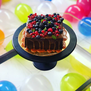 A chocolate cake topped with fresh berries and a glossy ganache finish.