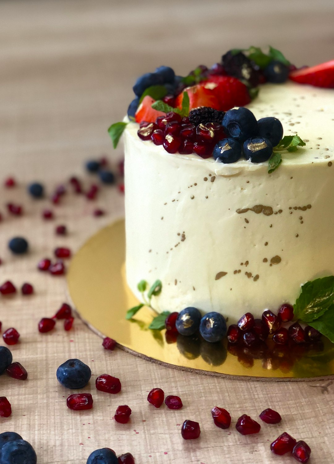 white cake with red and black berries on white ceramic plate