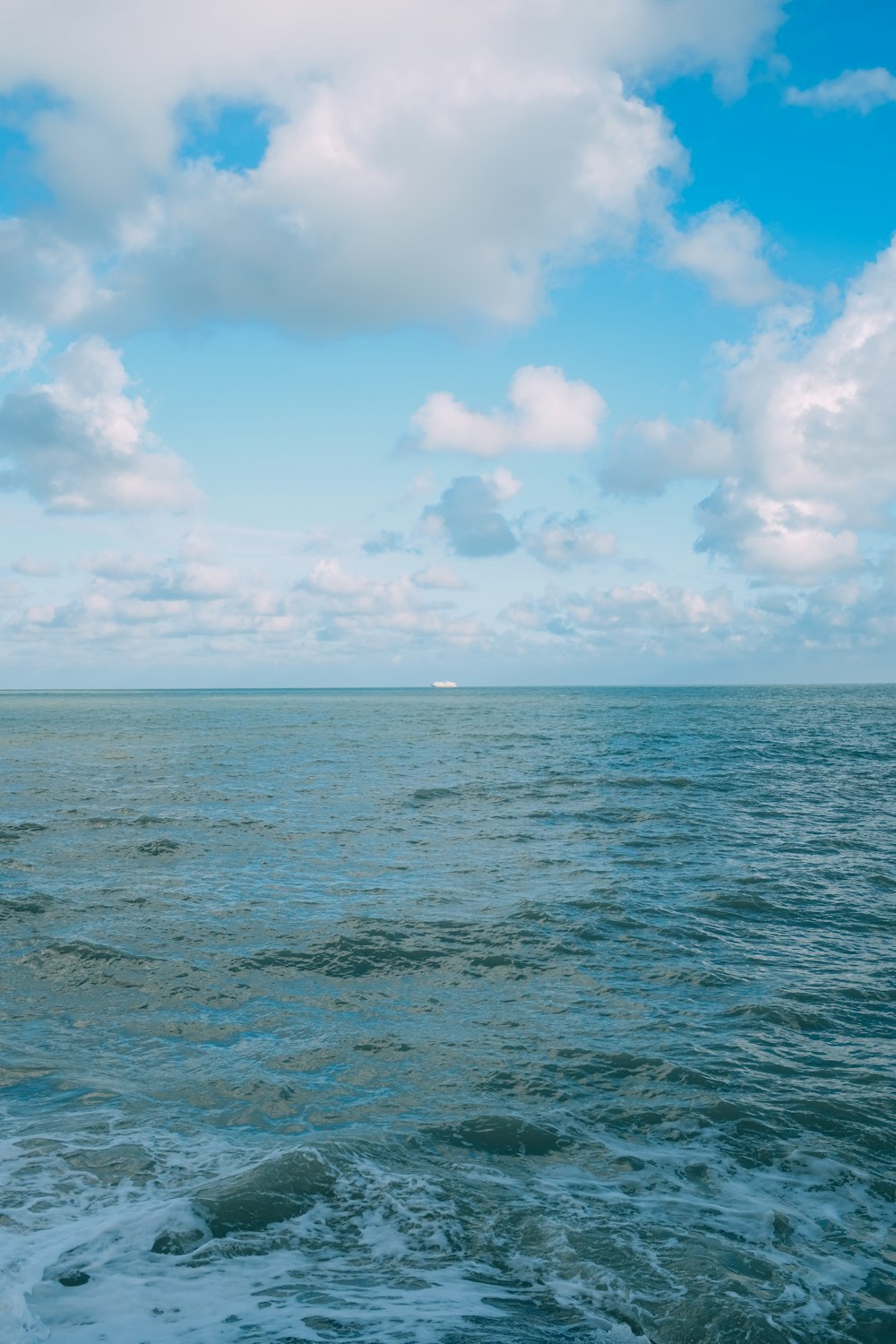 blue ocean under blue sky and white clouds during daytime