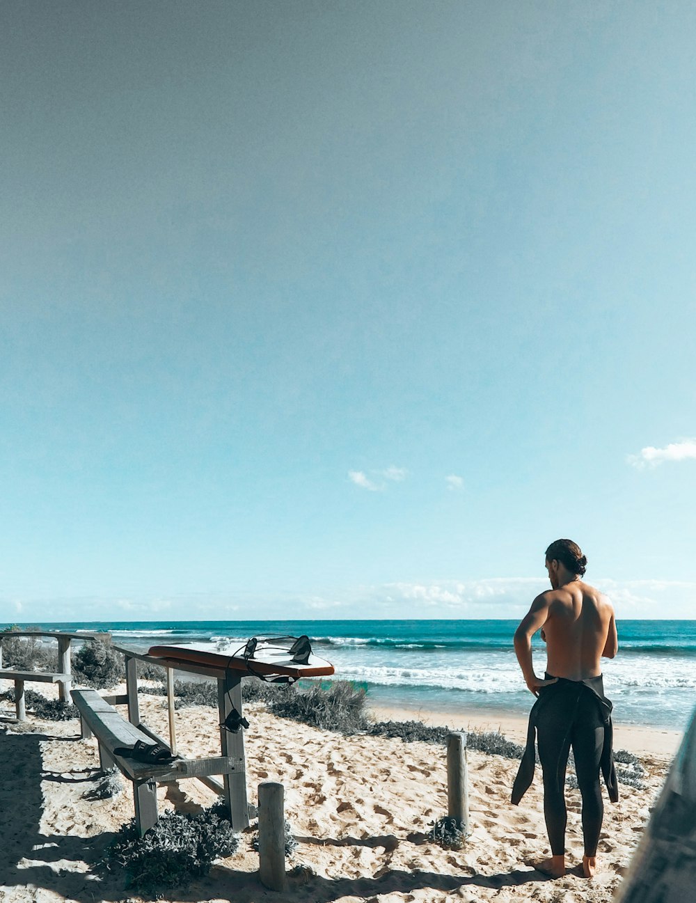 uomo in pantaloncini neri in piedi sulla spiaggia durante il giorno
