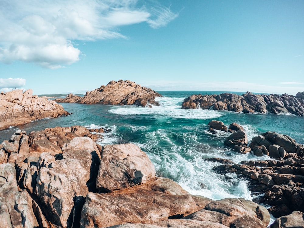 brown rocky mountain beside blue sea under blue sky during daytime