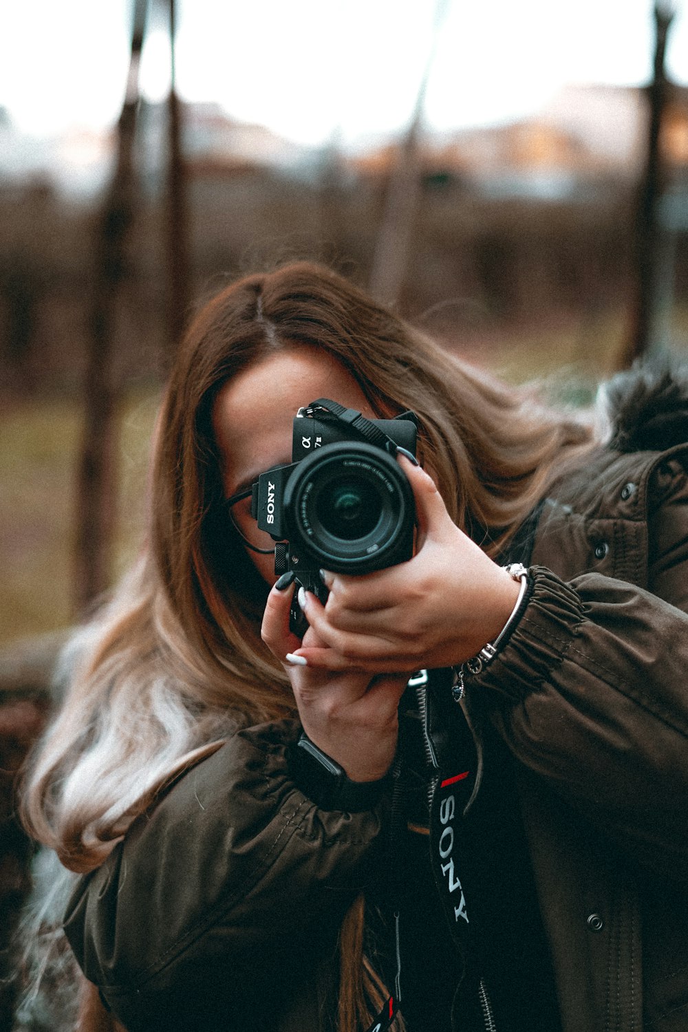 woman in black jacket holding black dslr camera