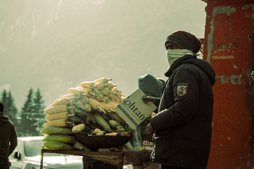 Des gens en veste noire debout devant des légumes verts et jaunes