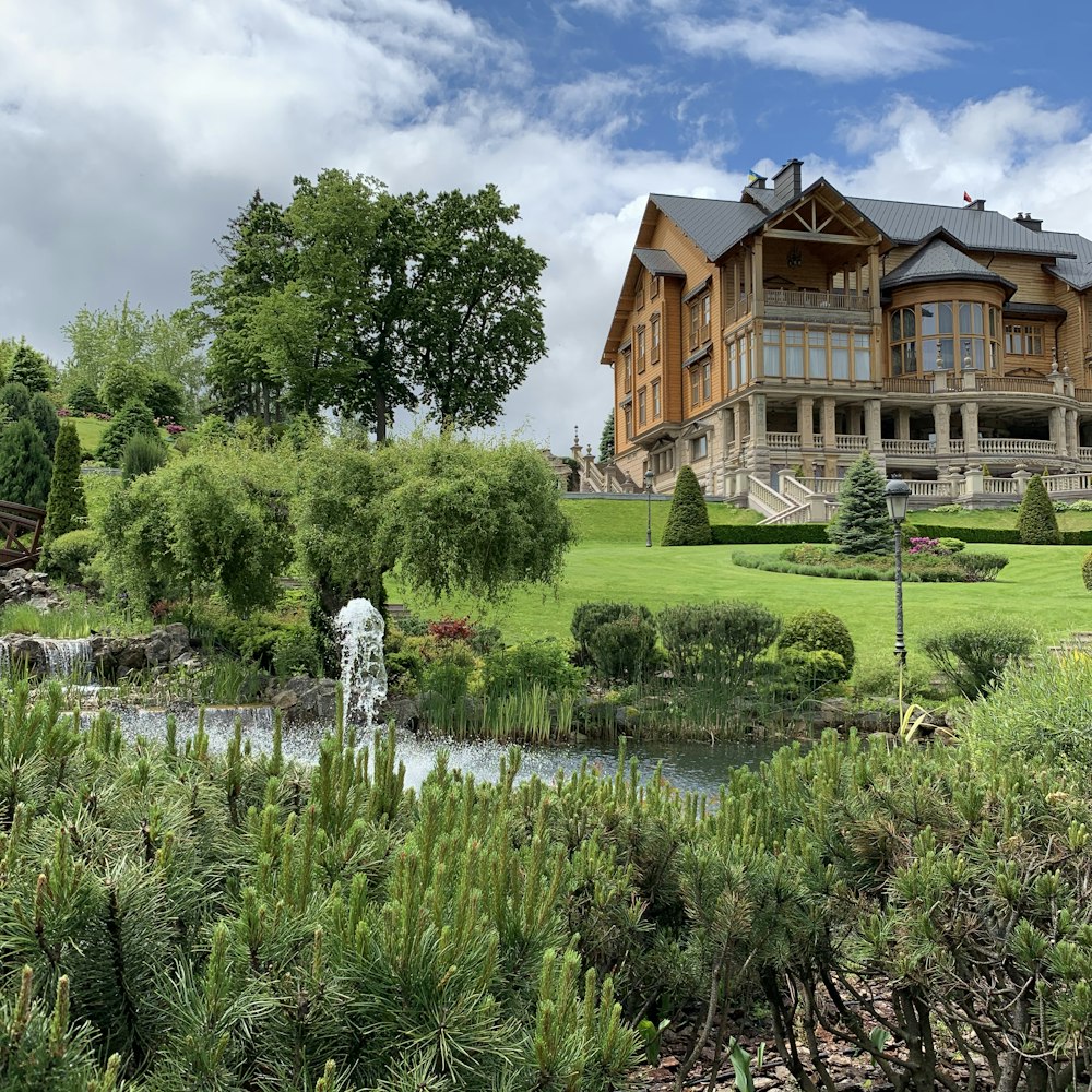 brown and white house near green trees under white clouds and blue sky during daytime